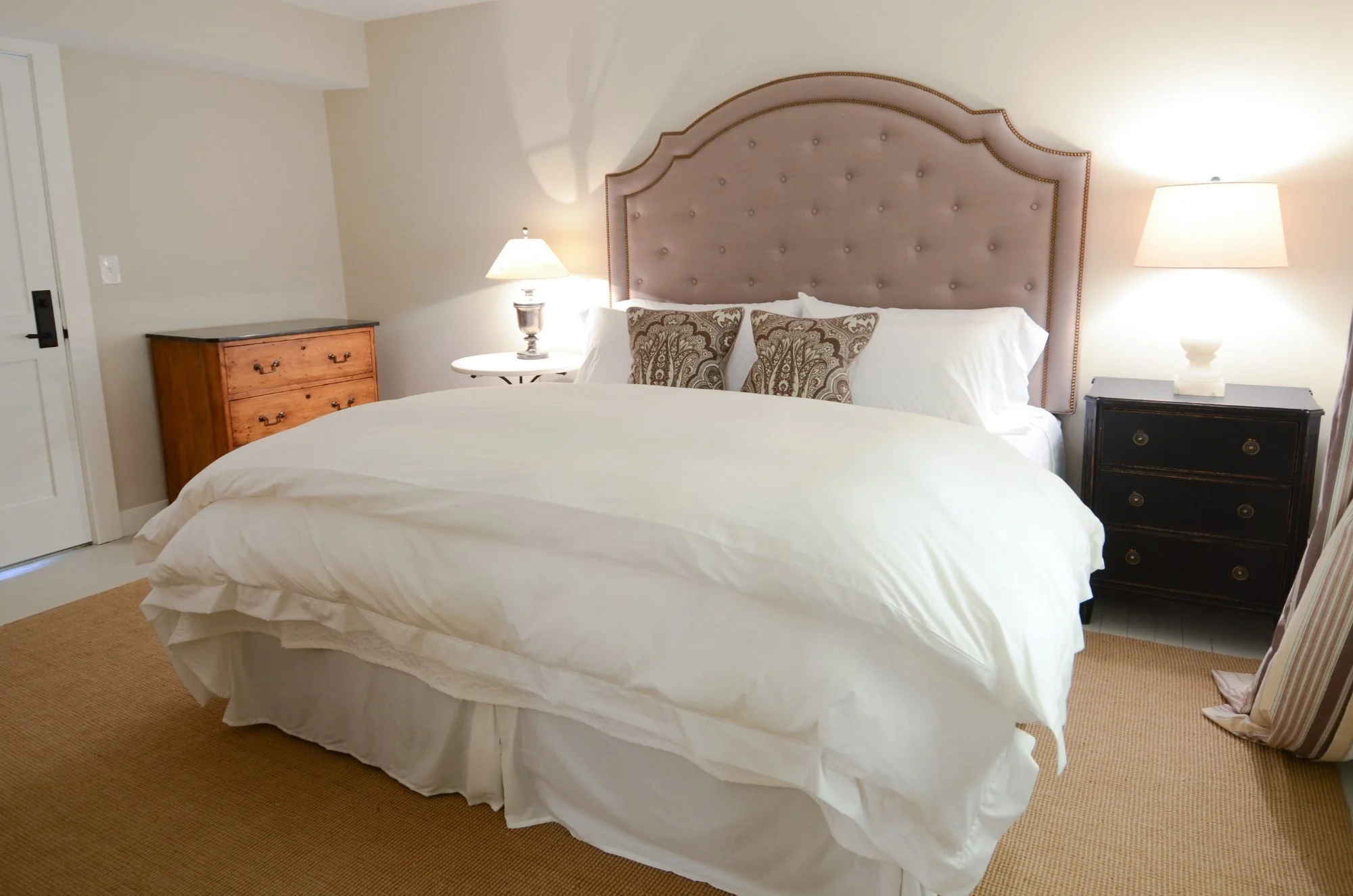 The Derby: a king bed with a mauve tufted headboard between two lamps.