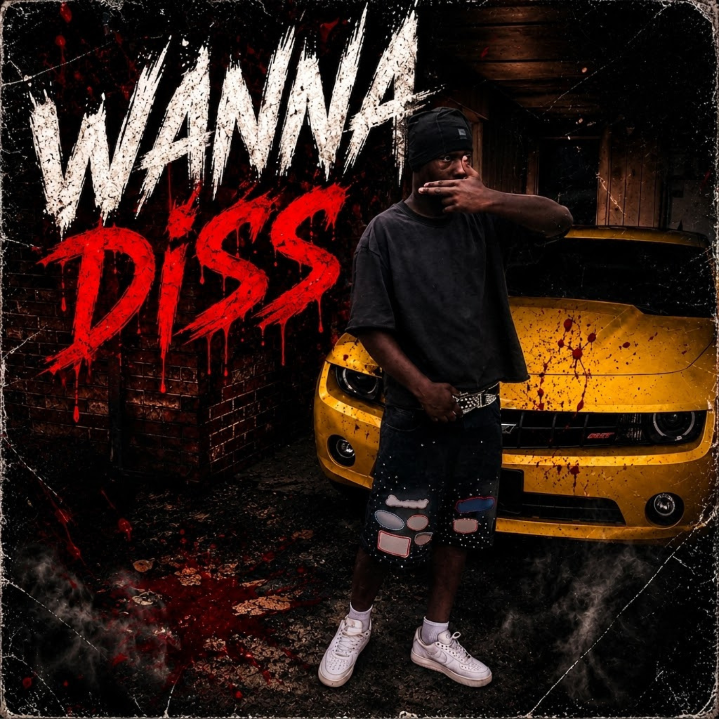 A young man wearing a black beanie, black oversized T-shirt, shorts with patches, and white sneakers stands in front of a yellow sports car with blood splatter on the hood. Blood splatters are on the ground, and a painted wall backstage reads 'Wanna Kiss Dvz' in stylized red and white letters. The setting is dark and gritty, with a blood-splattered, rough aesthetic.