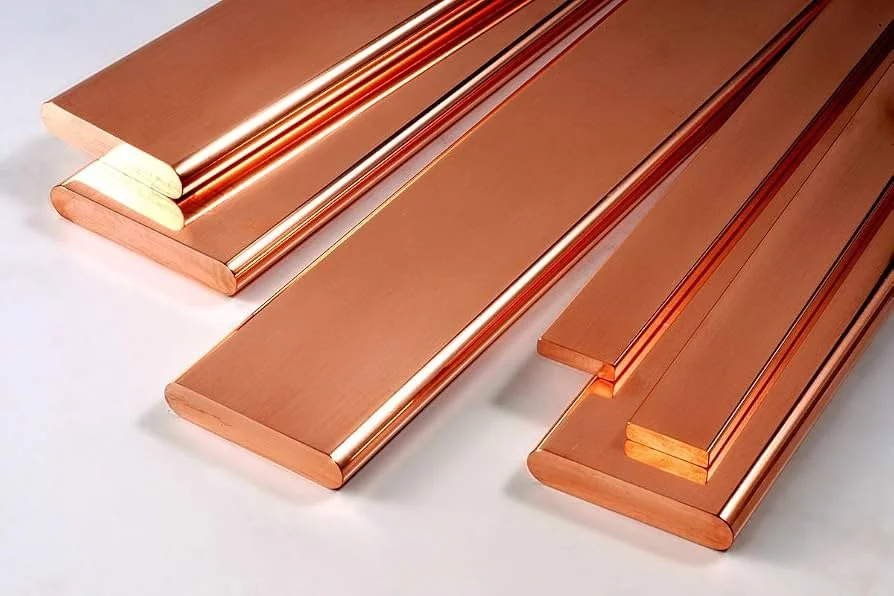 Varillas de cobre pulidas y cortadas, colocadas sobre una superficie blanca.