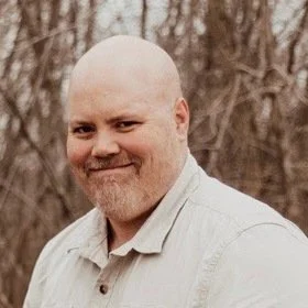 Jeff Wooldridge smiling outdoors in front of trees.