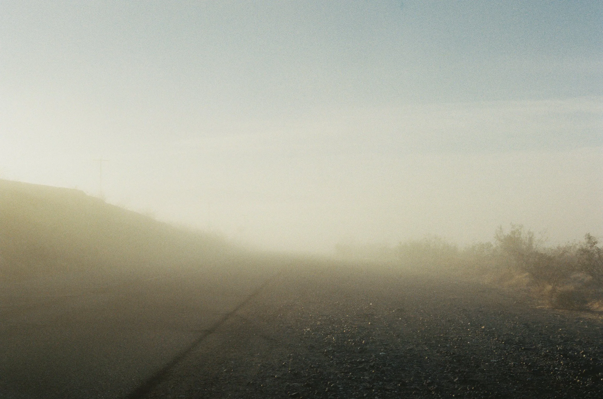A desert road is barely visible covered in morning haze.