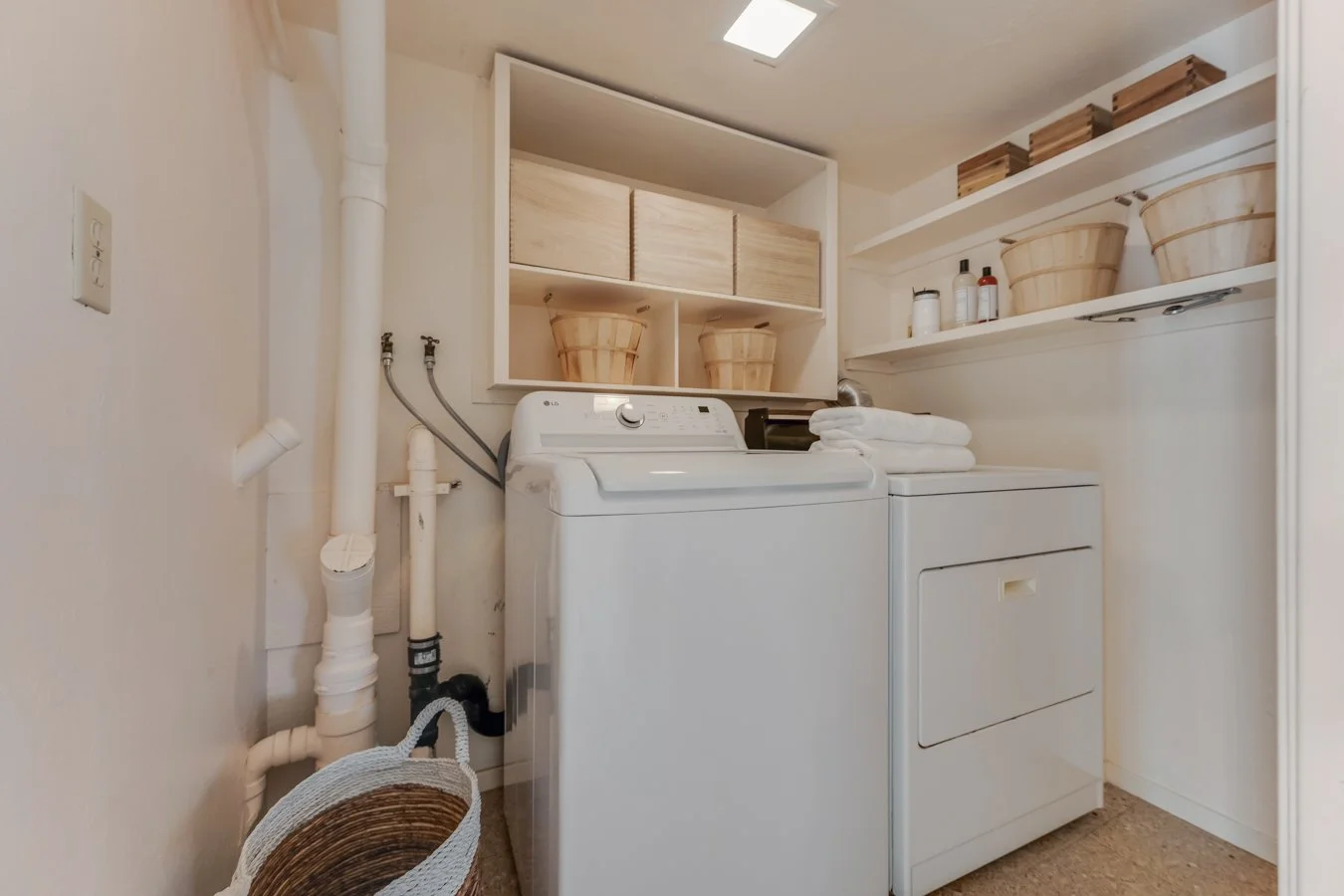 A laundry room with a washing machine and dryer, shelves with baskets and toiletries, and folded towels.