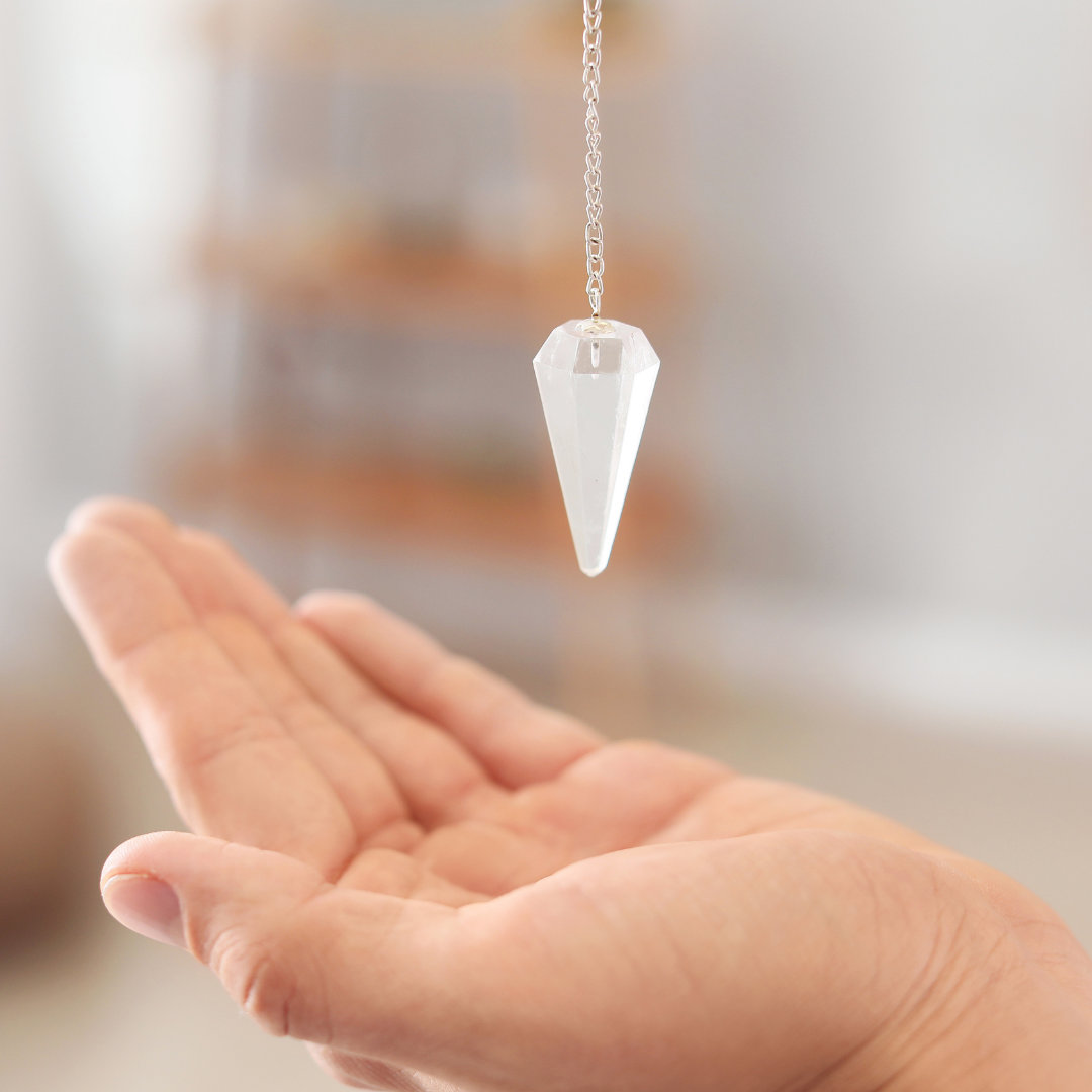 Crystal pendulum held above an open hand