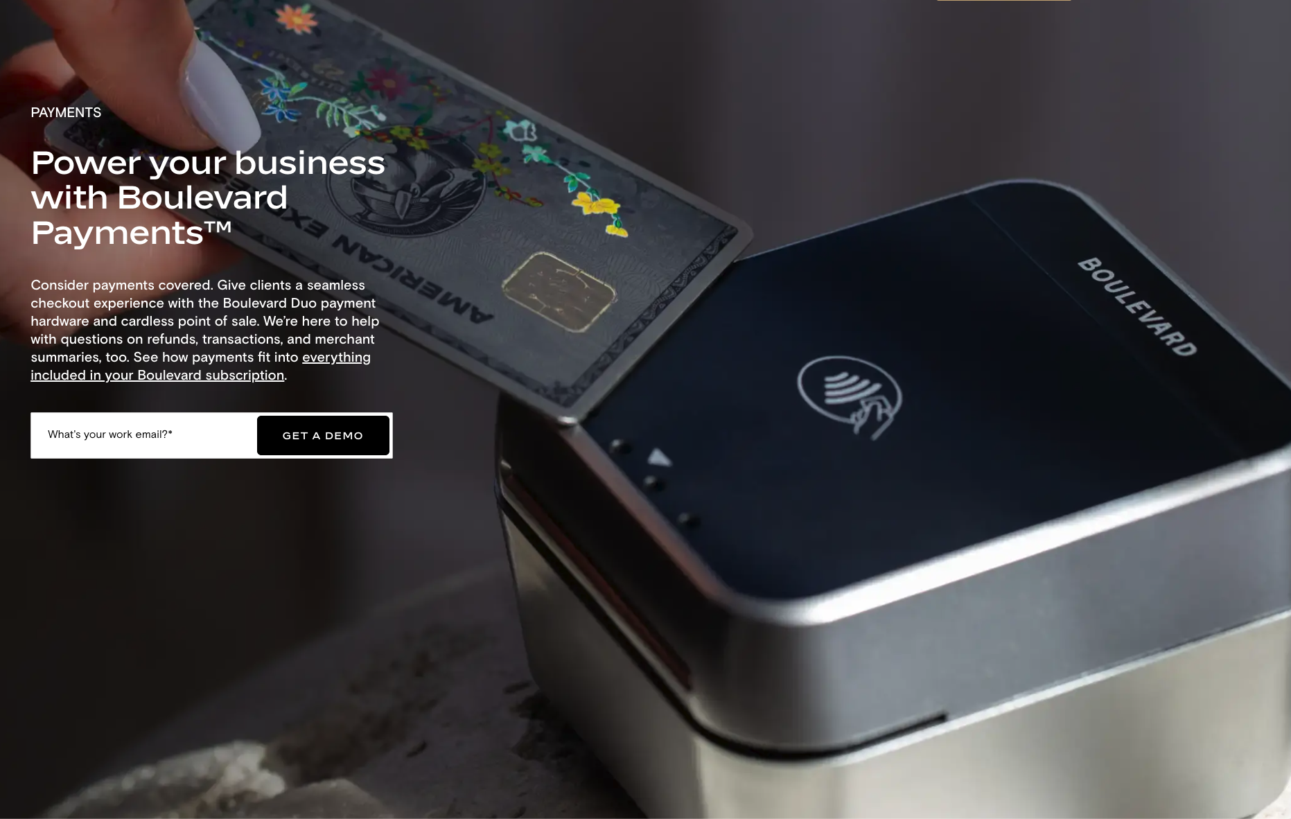 Close-up of a contactless payment terminal processing a credit card with a floral design, with a smartphone nearby, on a dark surface.