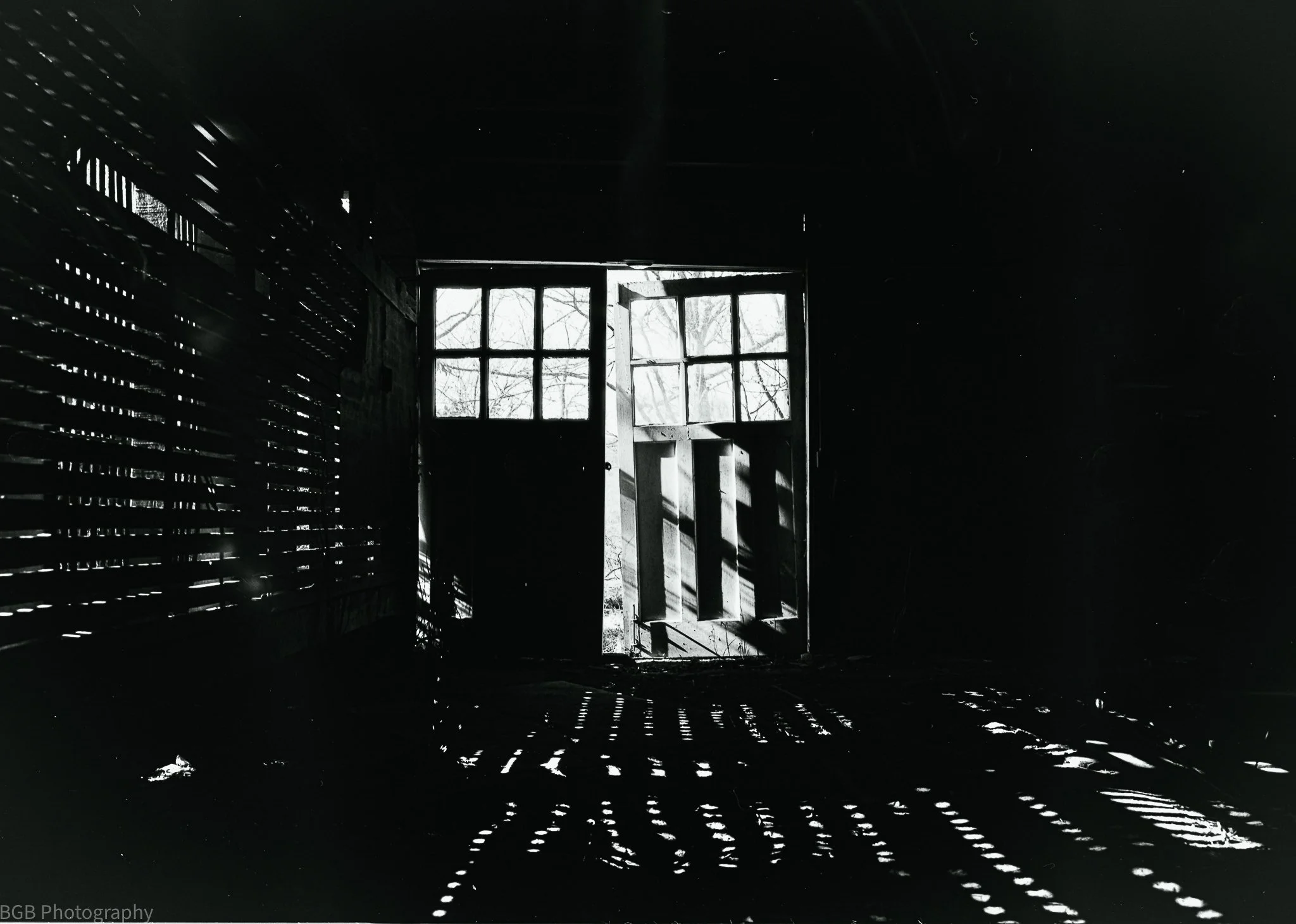 Inside a dark room with sunlight coming through a window, casting shadows and light patterns on the floor and walls.