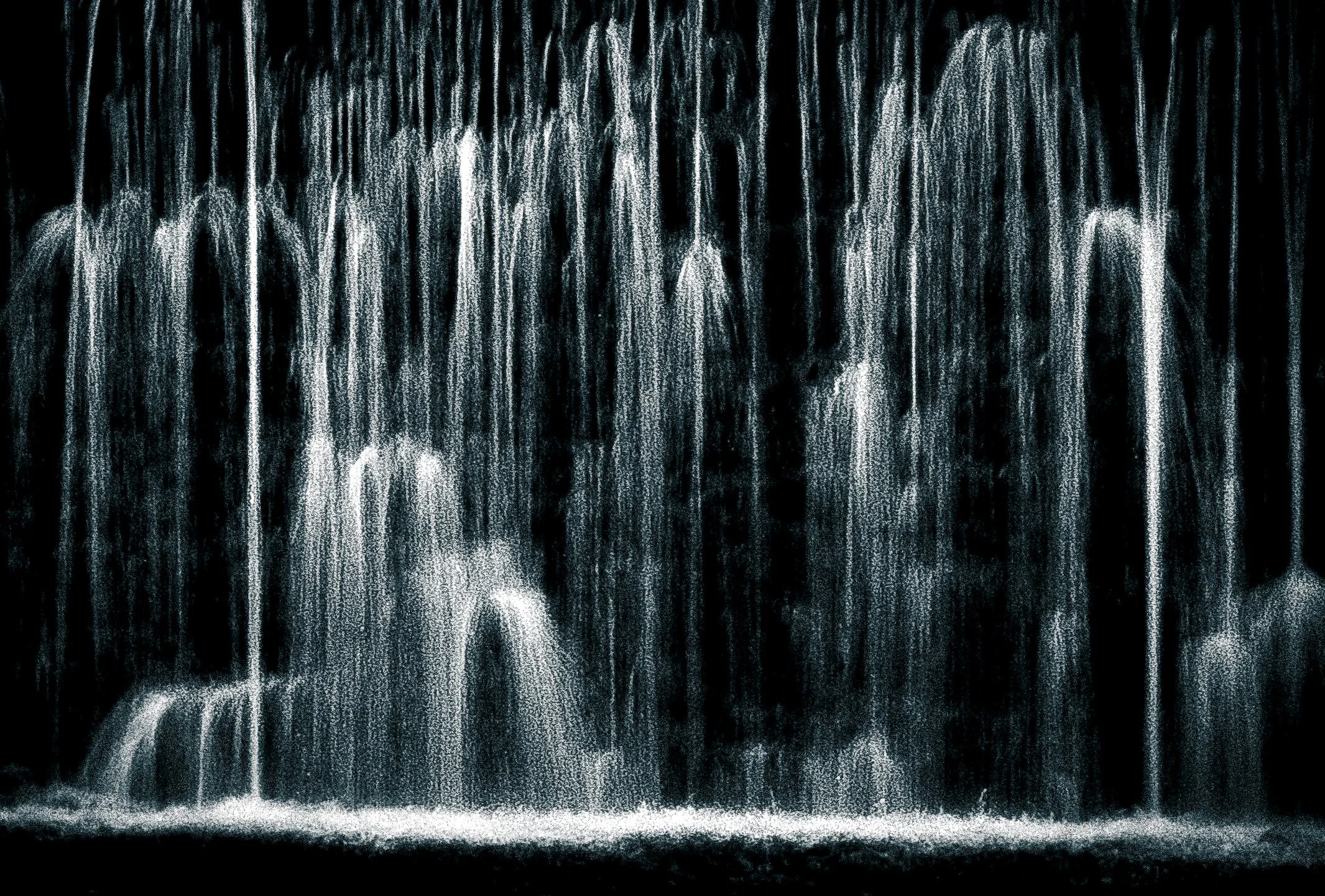 Rainbow-colored waterfall with cascading water falling into a stream.
