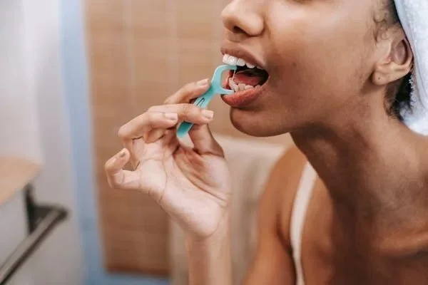 Person using a tongue cleaner in their mouth.