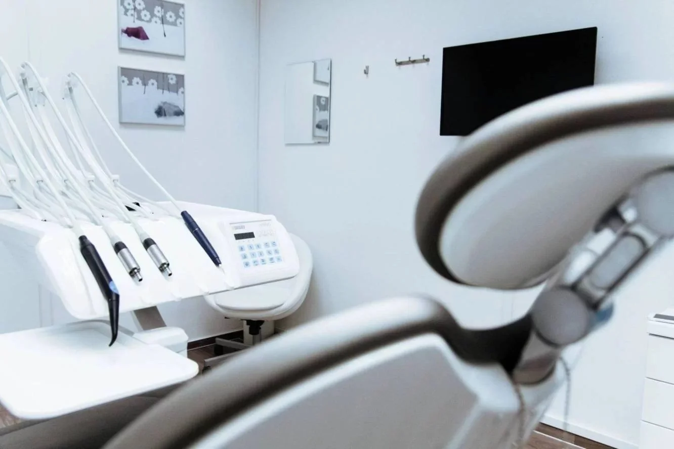 Dental examination room featuring dental tools, a dental chair, a television on the wall, and artwork.