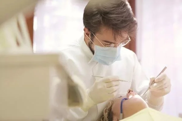 Dentist wearing a mask and gloves performing a dental procedure on a patient in a dental office.