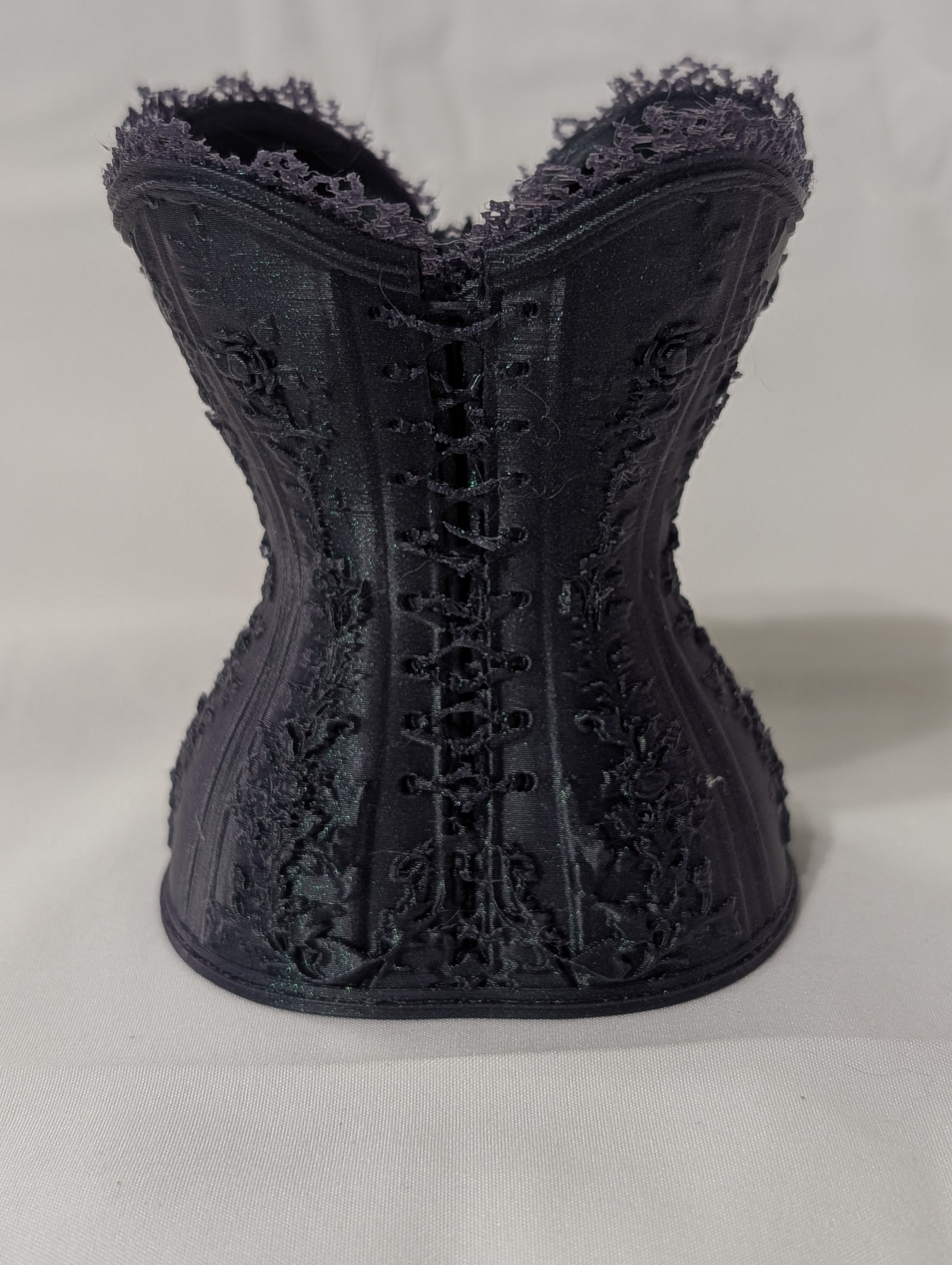 Black lace corset with intricate embroidery, laced up in the front, displayed against a plain white background.