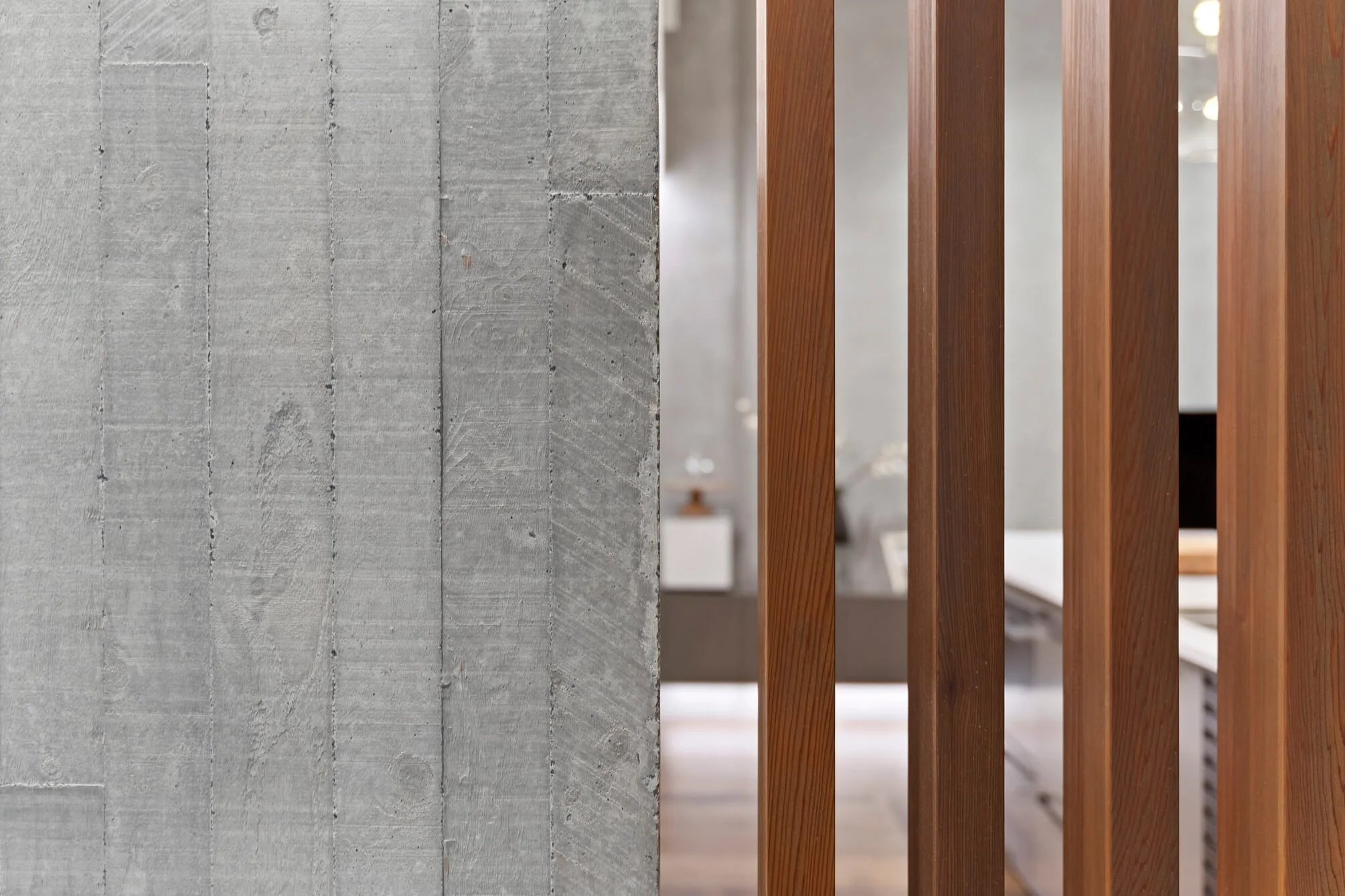 A close-up view of a concrete wall and wooden slats, with the wall on the left side and the slats on the right side.