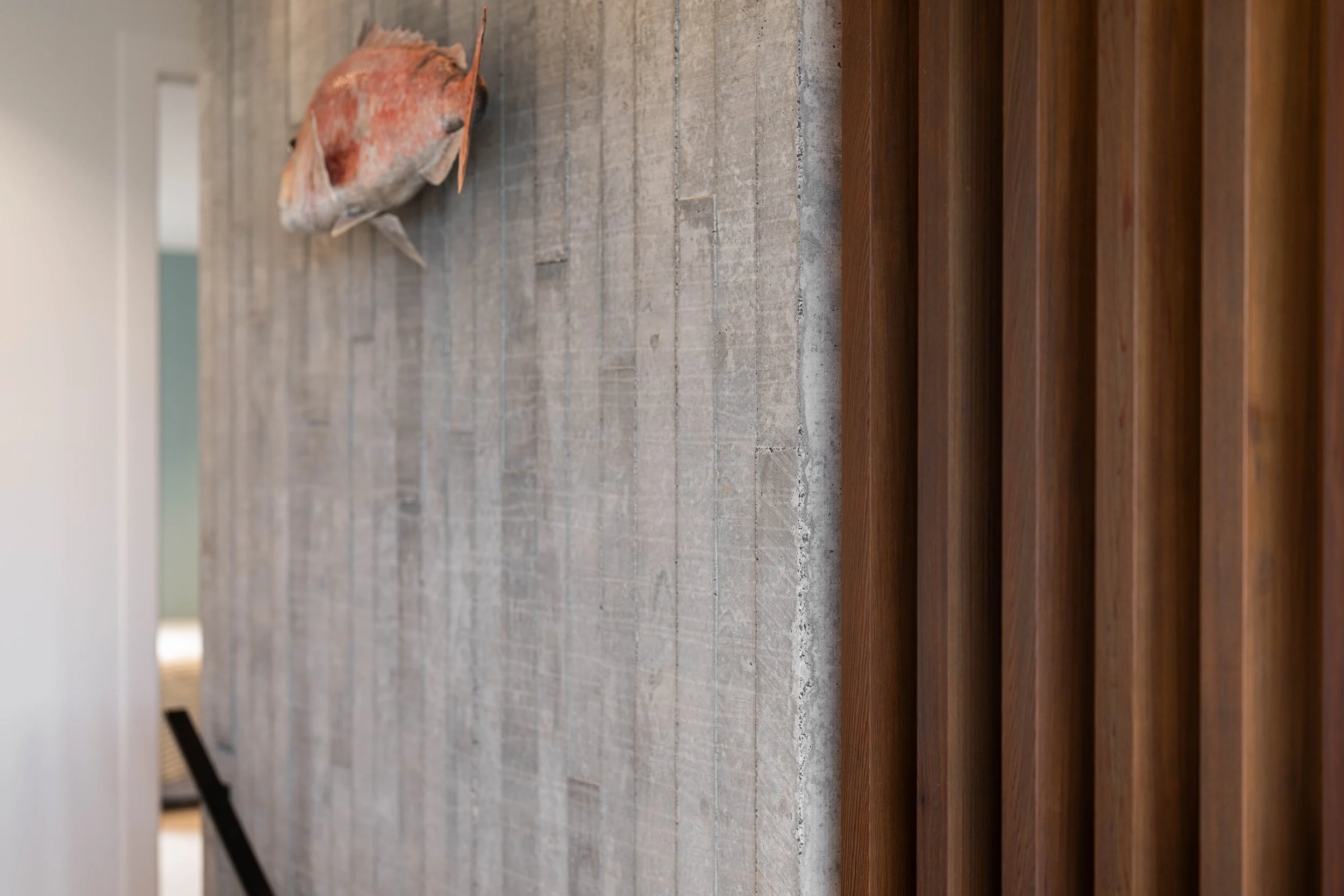 Close-up view of a fish mounted on a wooden surface with a light-colored brick wall in the background.