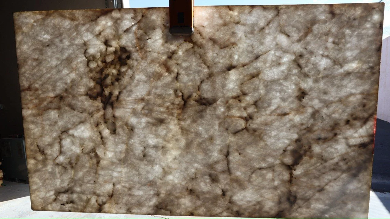 A large slab of polished beige and brown marble with a complex, veined pattern.