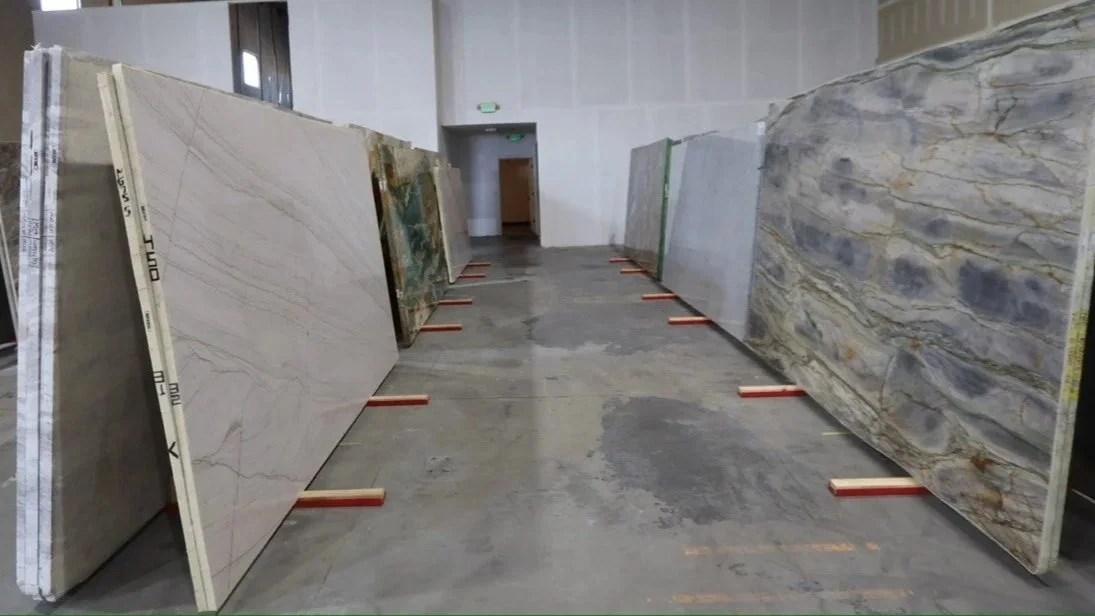 Large slabs of marble and stone displayed on stands inside a warehouse or showroom.