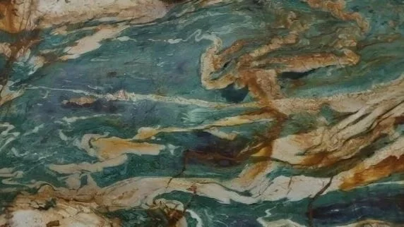 Close-up of a colorful marble or stone surface with swirling patterns of green, blue, brown, and white.