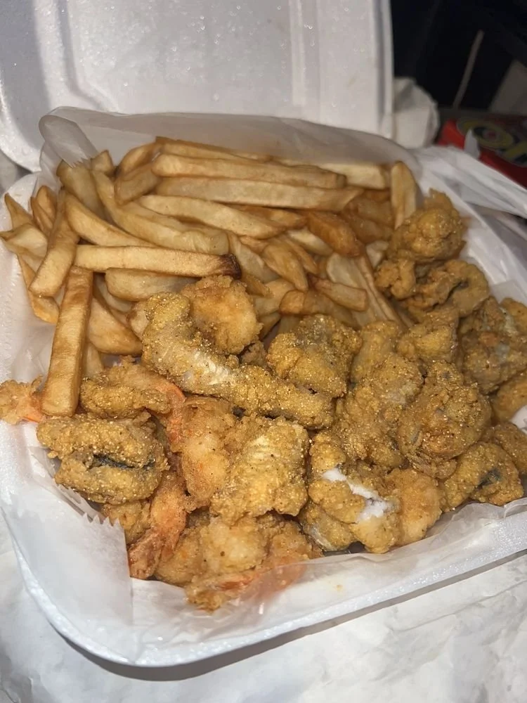 Fried fish pieces with French fries in a takeout container.