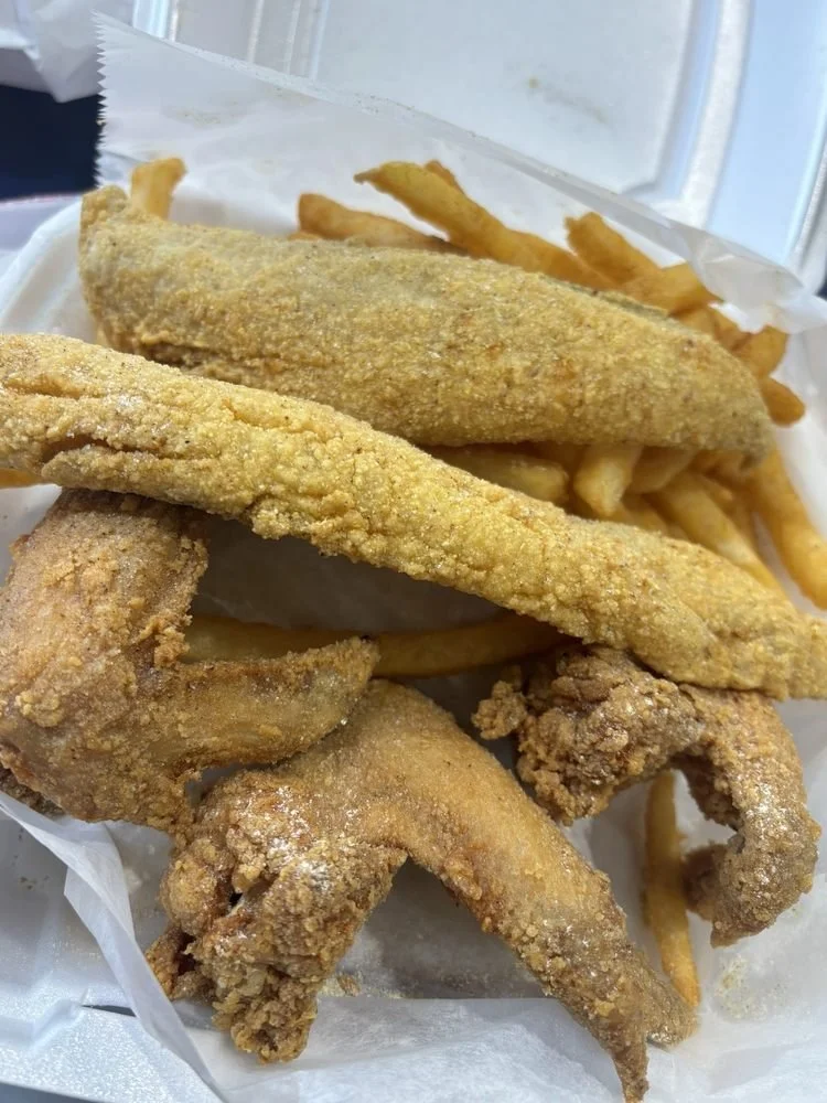 Fried chicken wings, French fries, and fried fish fillets in a takeout container.