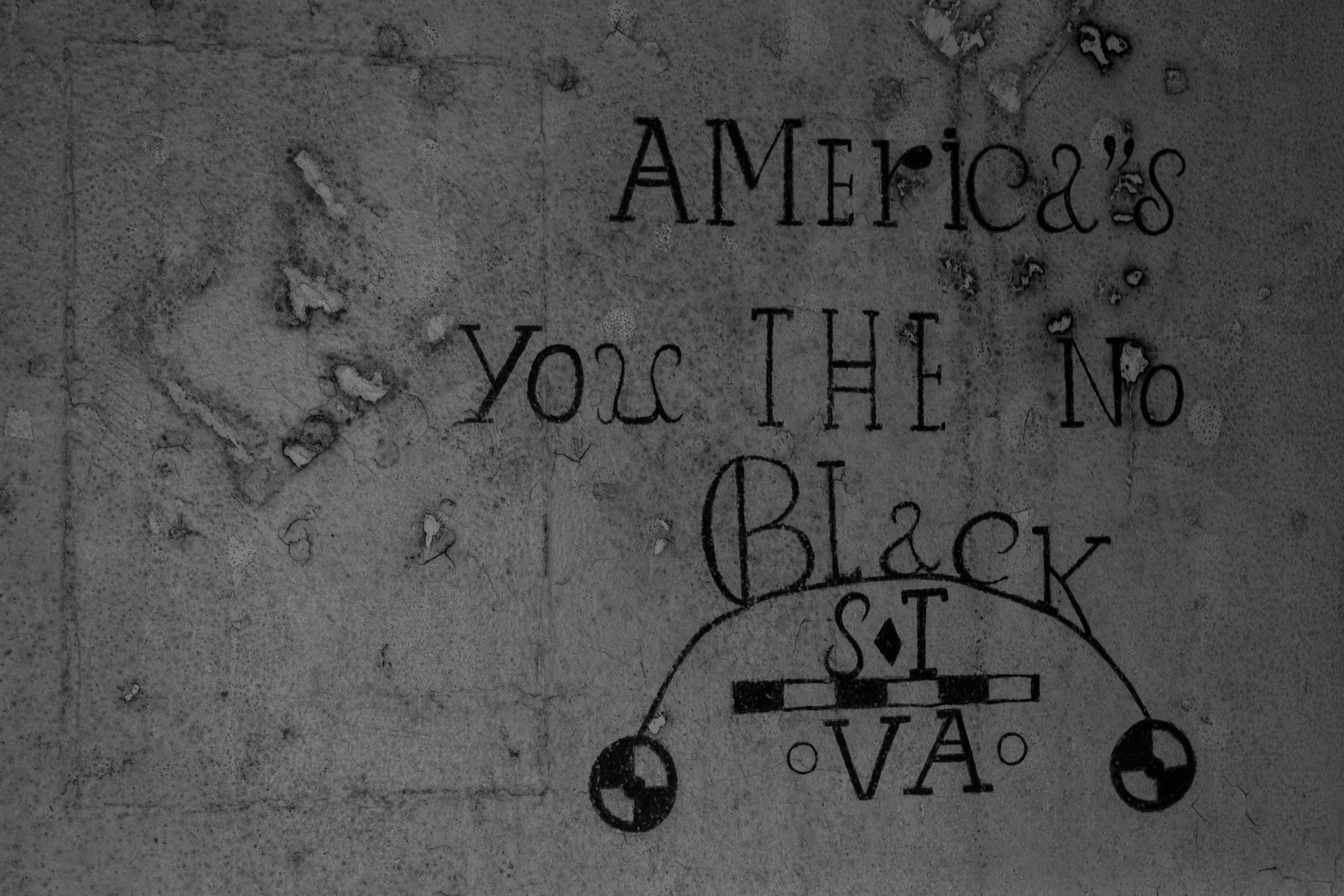 Close-up of a weathered, engraved stone surface with the partially visible phrase "America's" and some other text that is difficult to read.