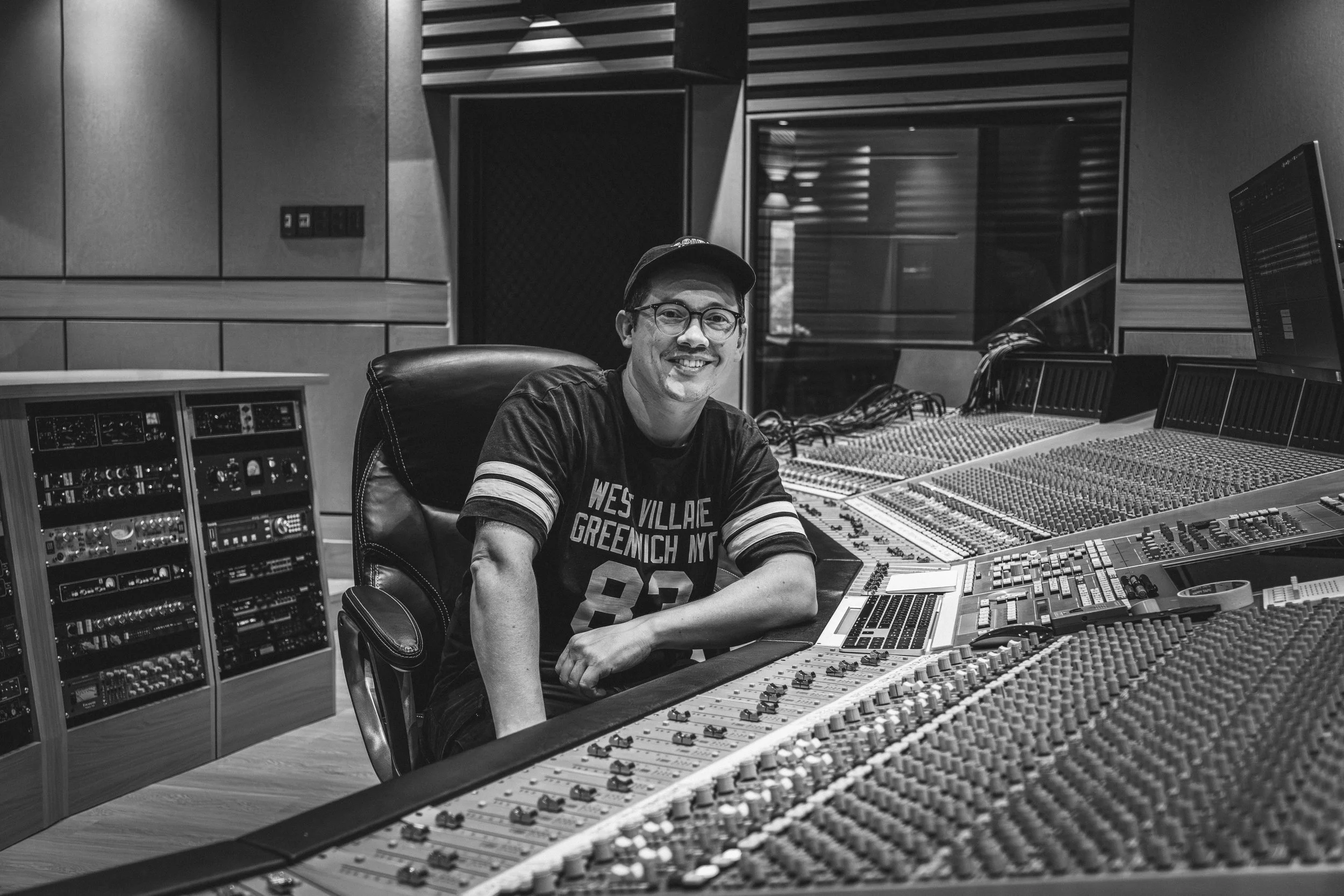 Benjamin James smiling to camera while sitting at an SSL 9000J mixing console.