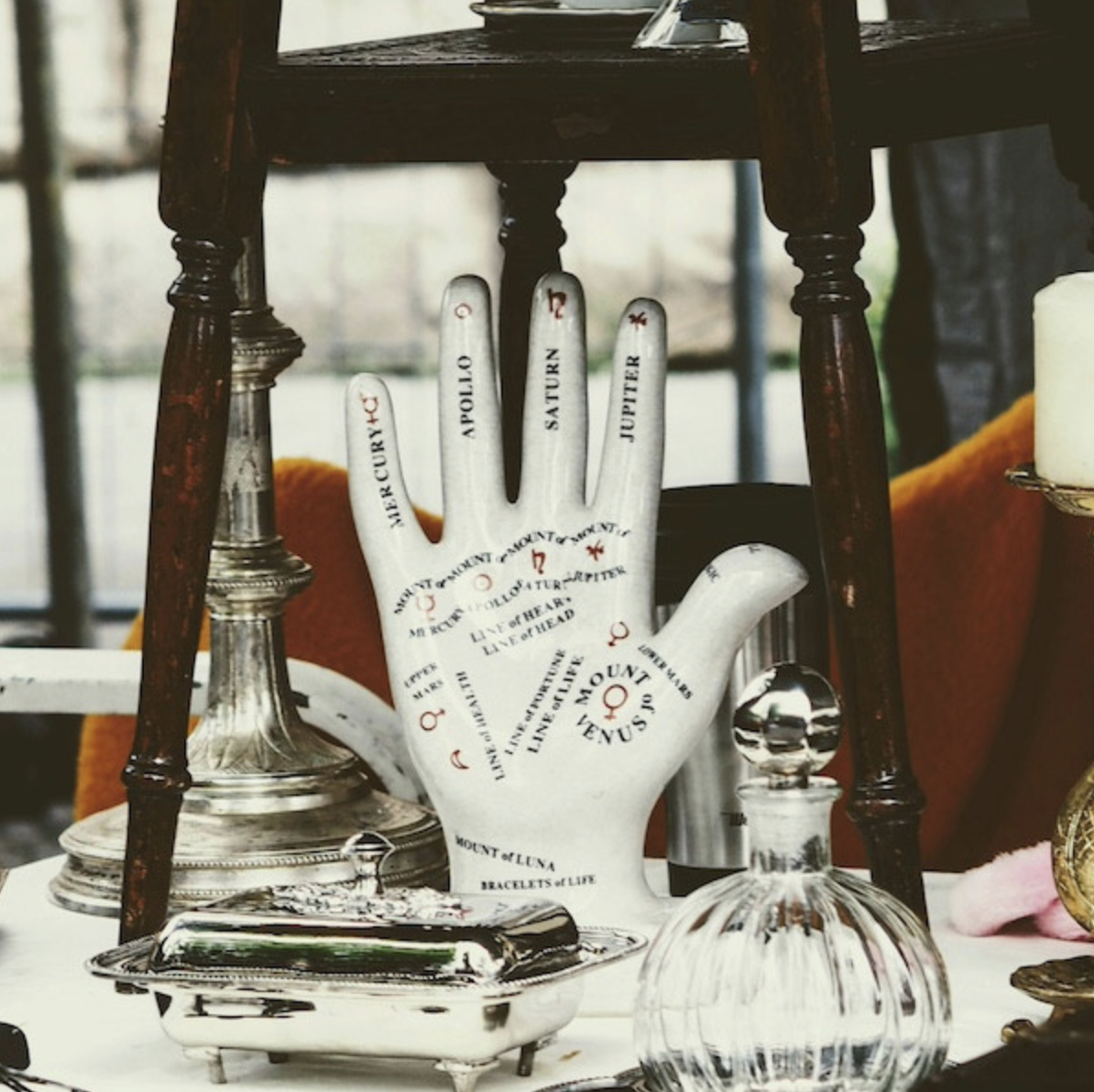 an upright ceramic hand with a palmistry map written out on it in red and black.