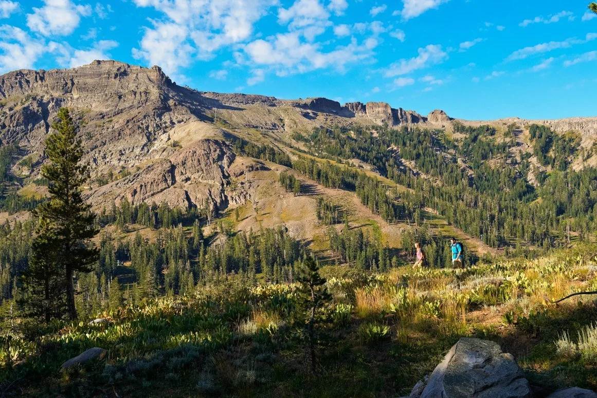 The ridge above Kirkwood in summer, with two hikers crossing the meadow below