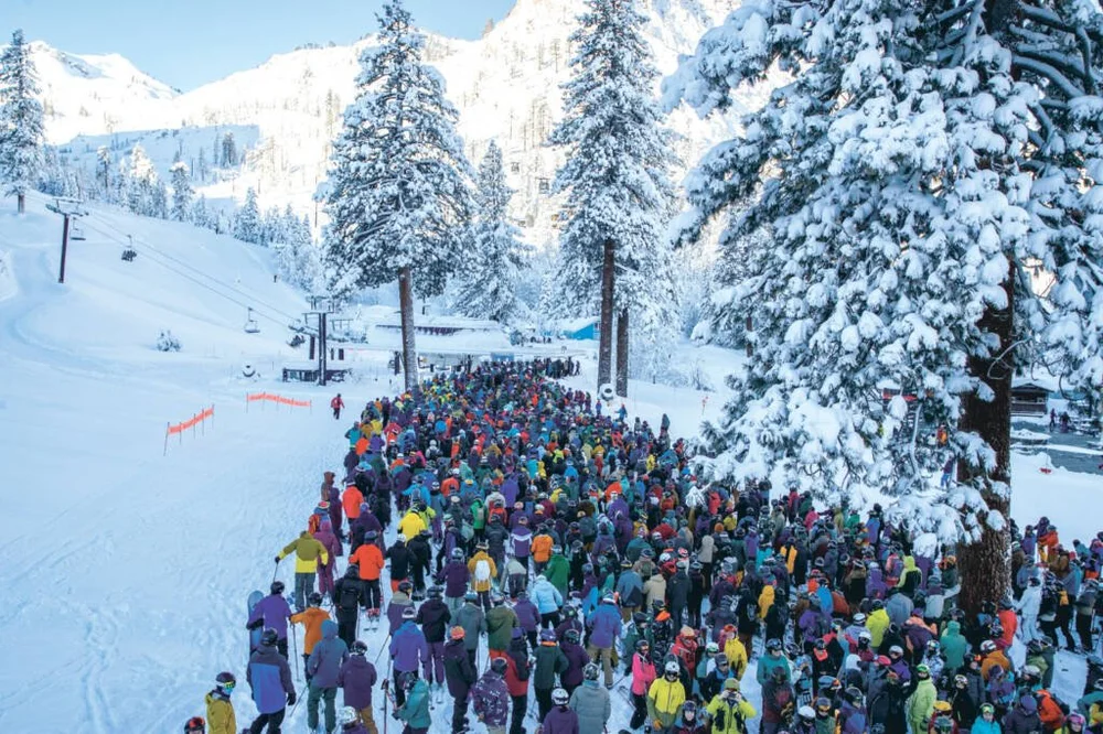 A long crowd of skiers waiting at a lift line