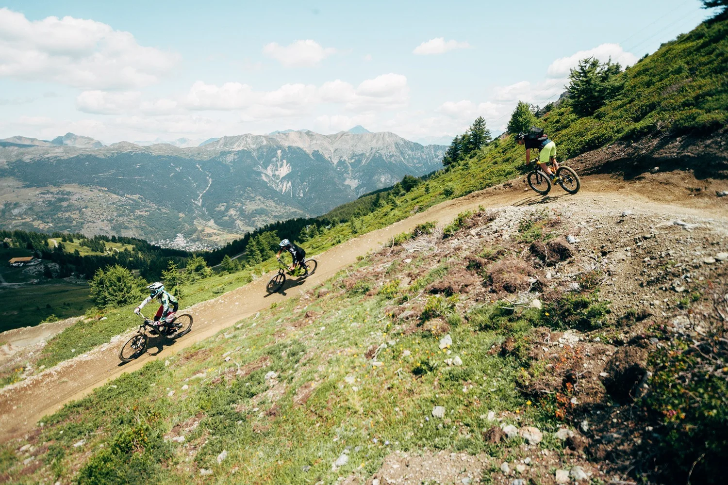 Mountain bikers on a summer trail above a valley