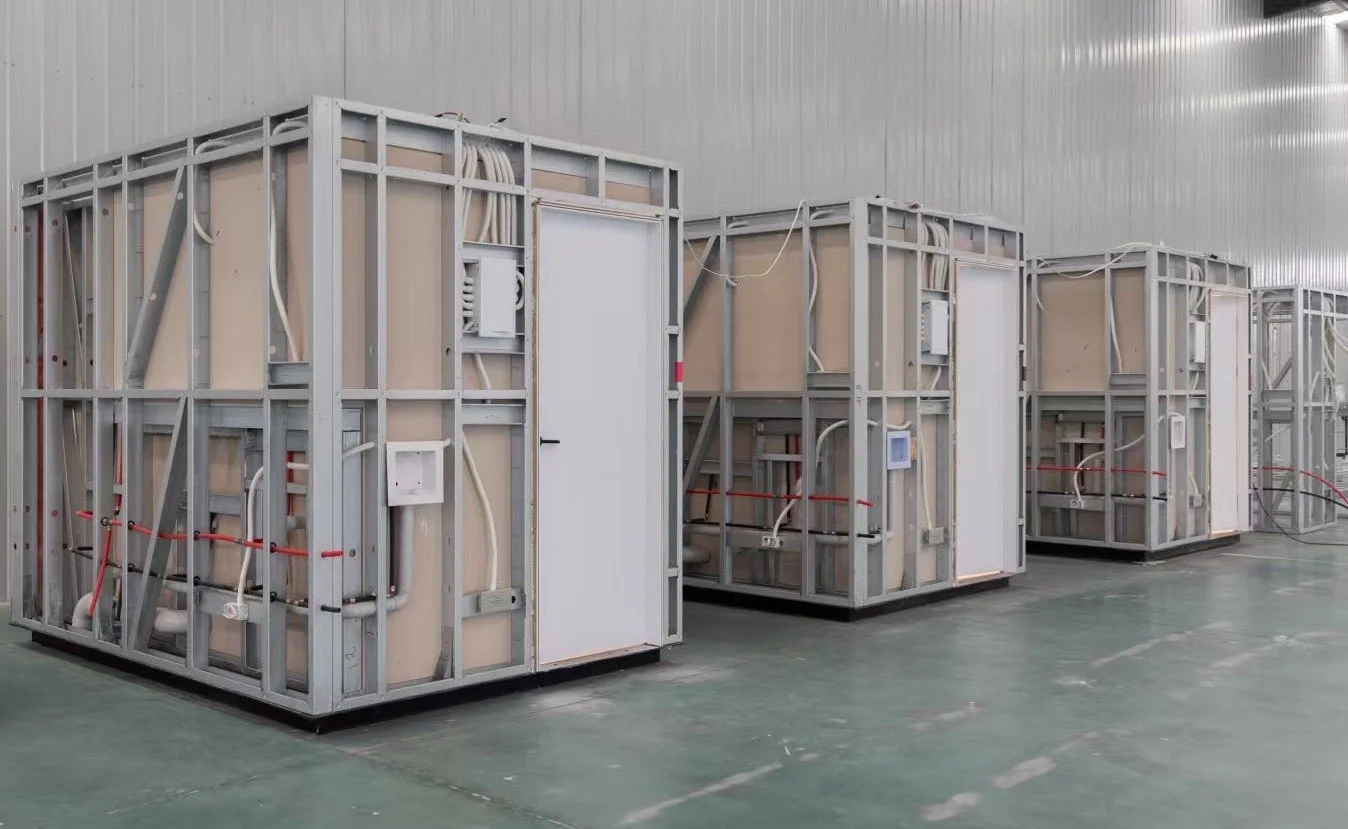 Steel-framed modular pods with plumbing and wiring, inside a factory