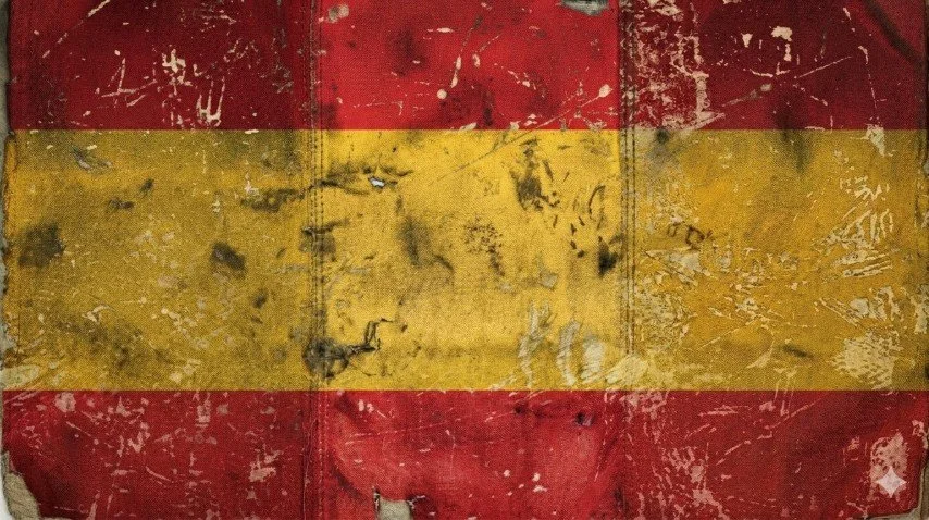 A weathered Spanish flag with red and yellow horizontal stripes, appearing old and torn.