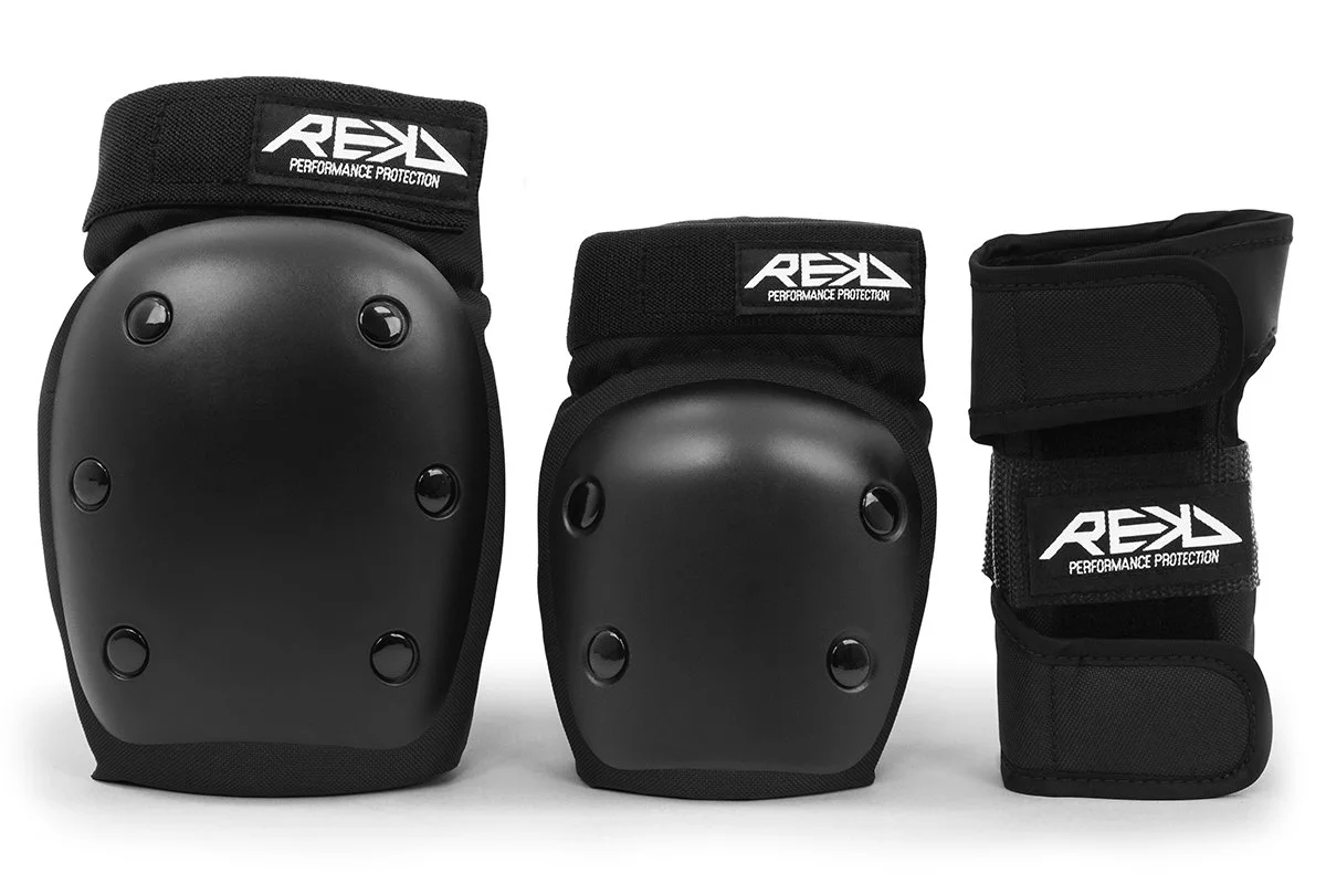Set of black protective knee and ankle pads with adjustable straps and the brand name 'REKD' printed on Velcro straps.
