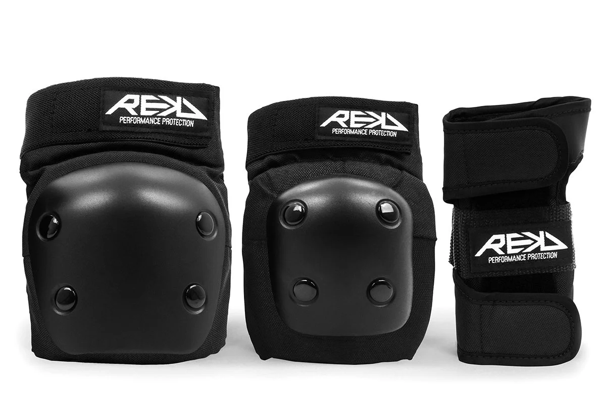 A set of black protective gear, including two knee pads with hard plastic caps and one wrist guard, all branded with REKD logo.
