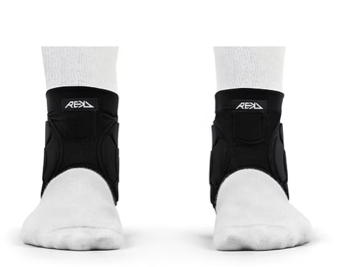 Pair of black ankle braces worn over white socks on feet