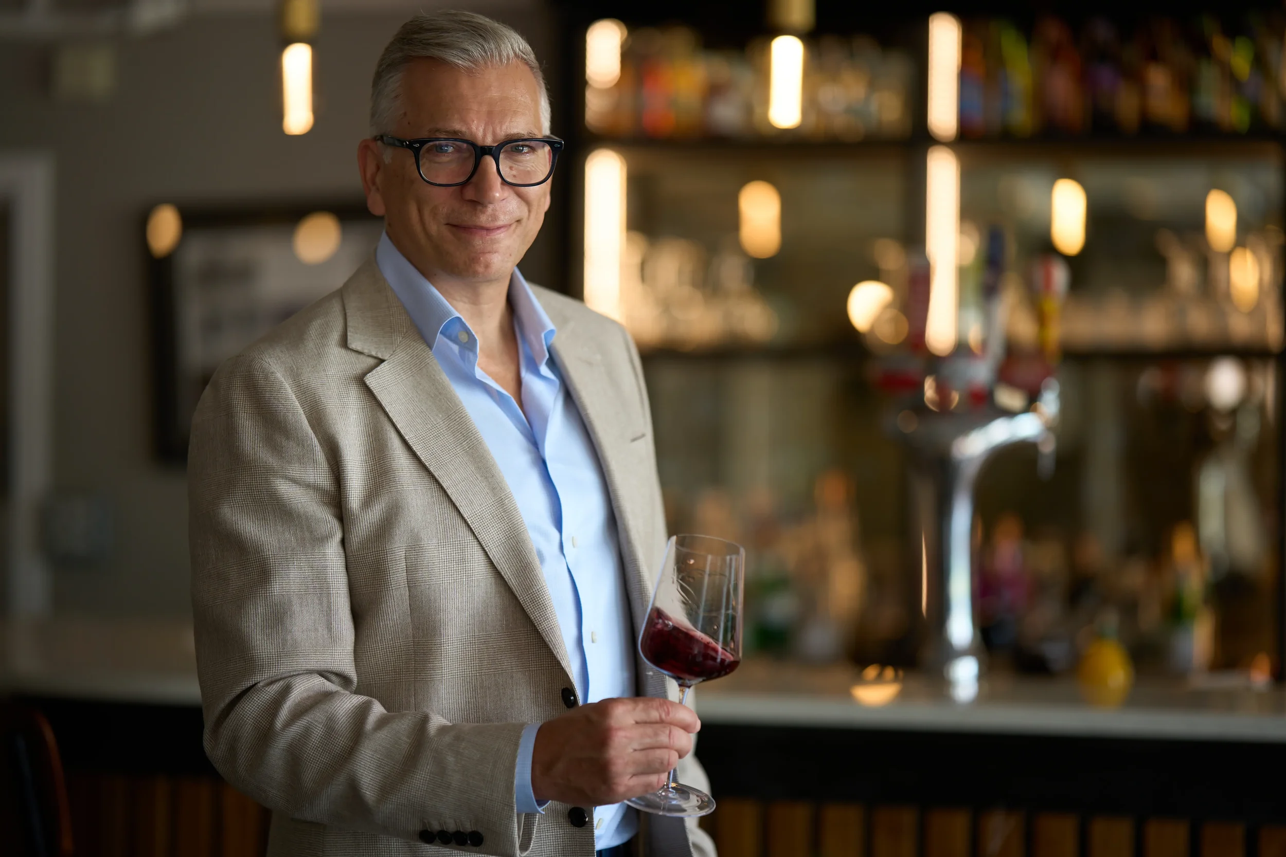 Mark Pygott MW holding a glass of wine in a bar