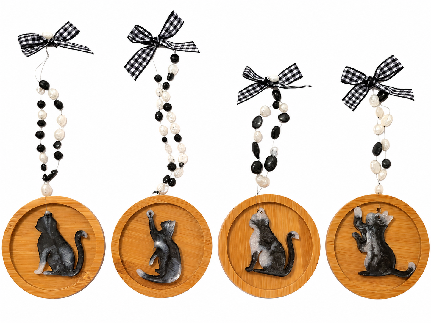 Four handmade black and white resin cat Christmas decorations on round wooden ornaments, featuring decorative black and white beads and gingham ribbon bows, displayed against a white background.