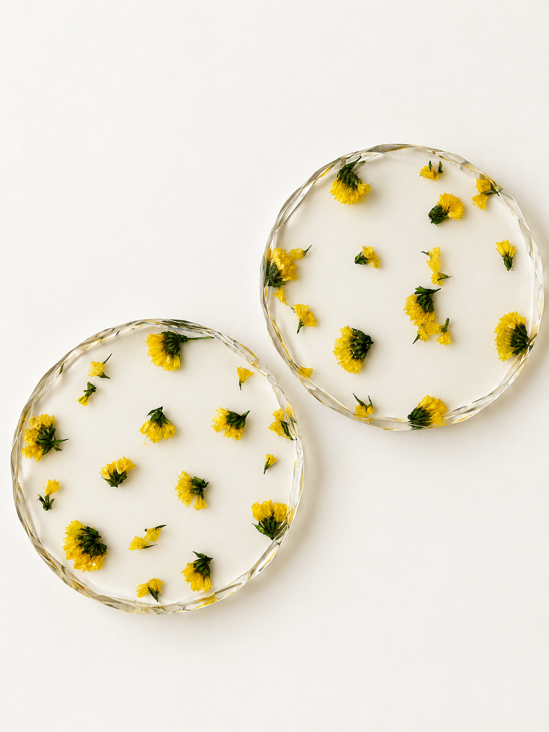Two glass bowls with yellow flowers on a white surface.