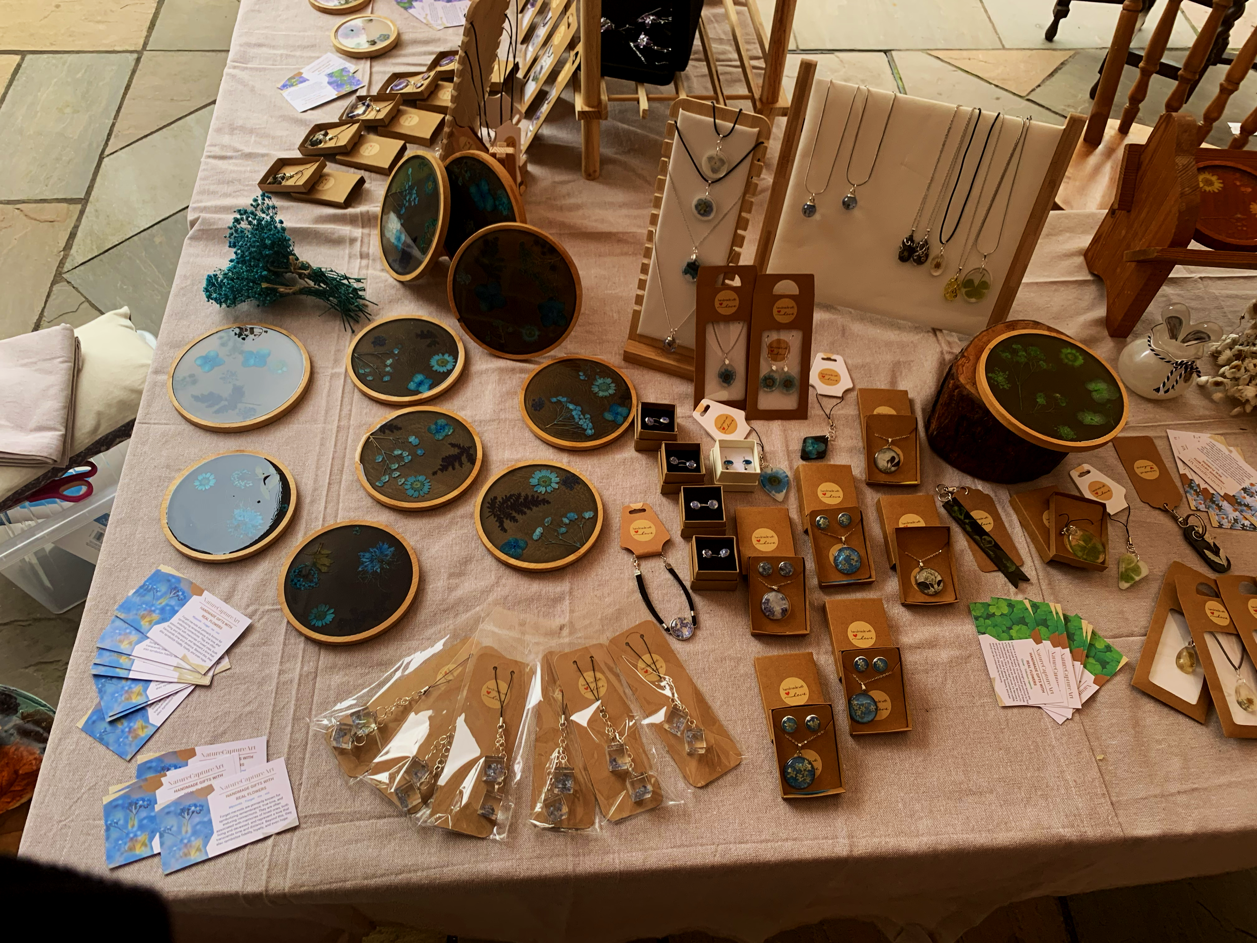 Display of handmade jewelry at a craft fair, including necklaces, earrings, and decorative items on a table.