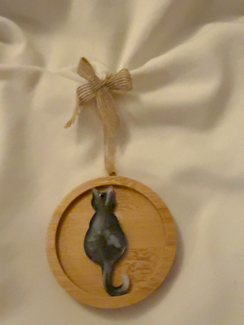 Handmade black and white resin cat Christmas decoration viewed from behind, on a 6.5 cm round wooden ornament with natural jute hanging loop and rustic hessian bow.