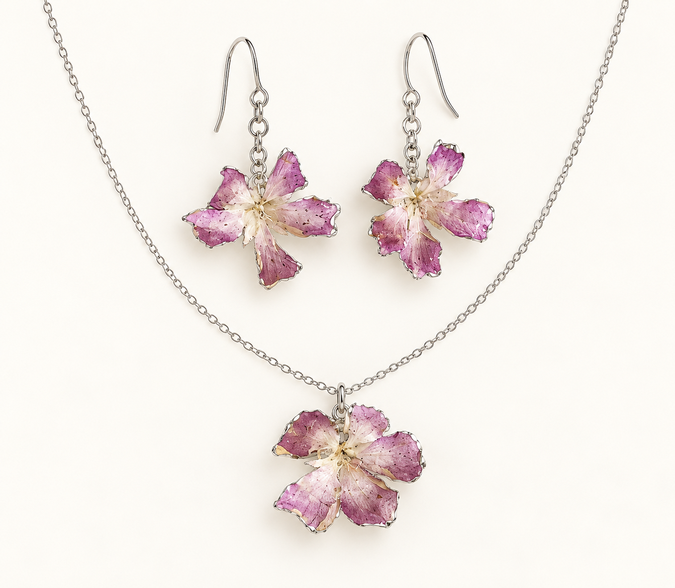 Silver necklace and earrings set with pink and purple flower-shaped pendants.