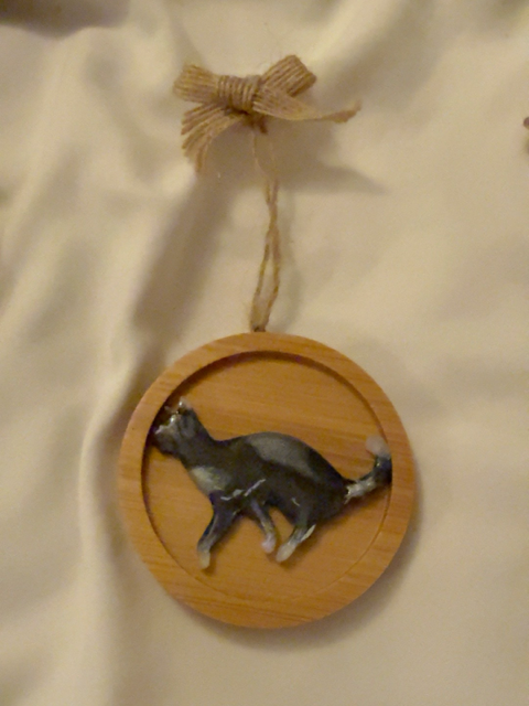Handmade black and white resin walking cat Christmas decoration ona 6.5 cm round wooden ornament, finished with a natural jute hanging loop and rustic hessian bow.