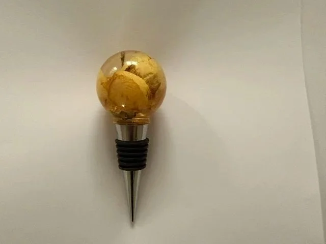 Handmade resinwine bottle stopper witha real preserved yellow rose inside a smooth round clear resin top.