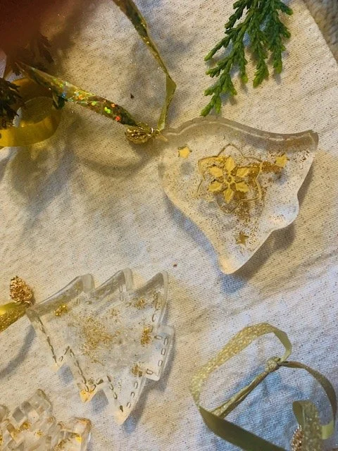 Handmade transparent resin Christmas ornament with decorative gold accents, showing with glossy finish and delicate festive detailoing.