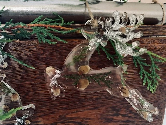 Handmade resin reindeer Christmas tree decoration featuring real preserved greenery, pine cone pieces and delicate silver sparkle, finished with a natural twine hanging loop.