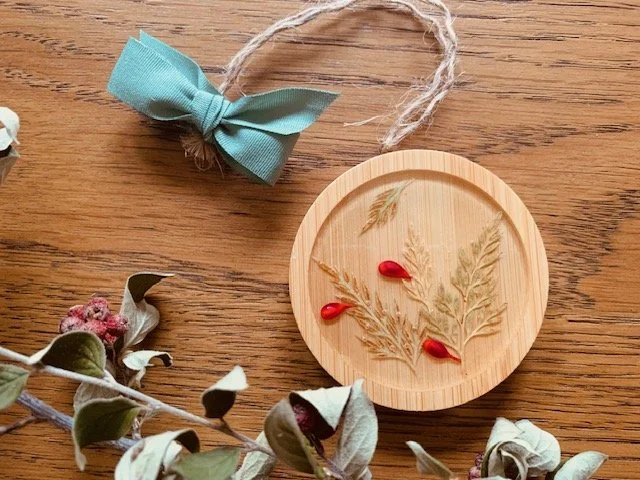 Handmade wooden Christmas tree decoration with real preserved greenery, artificial red berries, natural twine hanging cord and sage green ribbon bow.