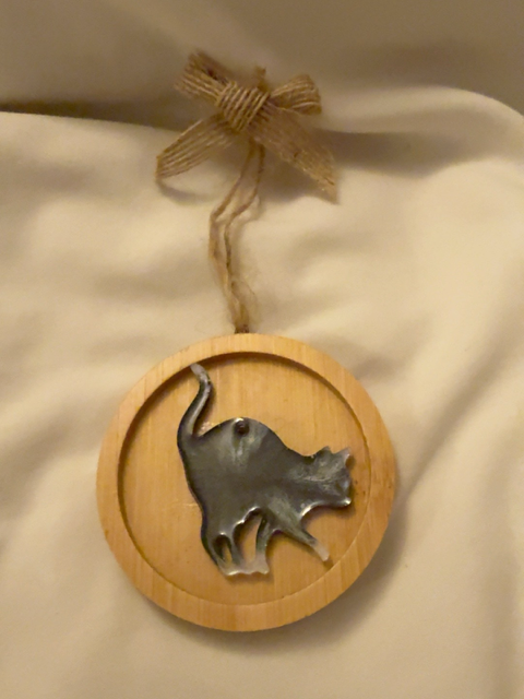 Handmade black and white resin cat Christmas decoration in a playful pose, displayed on a 6.5 cm round wooden ornament with natural jute hanging loop and rustic hessian bow.