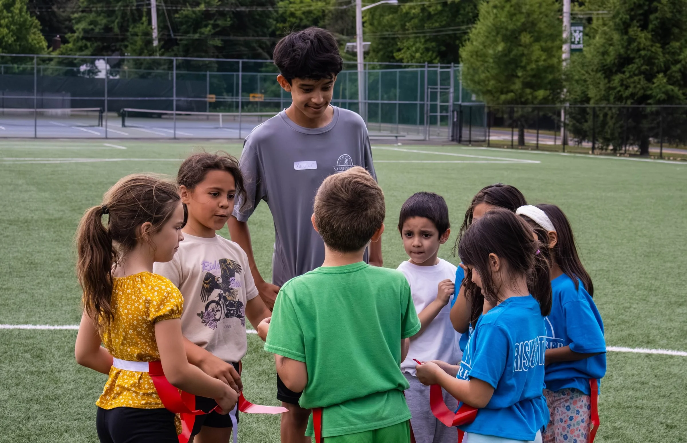 A counselor leading a circle of campers on the field