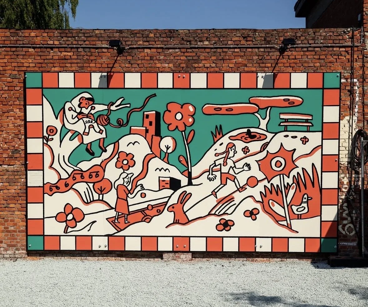Colorful mural depicting a whimsical outdoor scene with various cartoon-like characters, flowers, a rabbit, a dog, and playful elements, all outlined in red, white, teal, and black, on a brick wall.