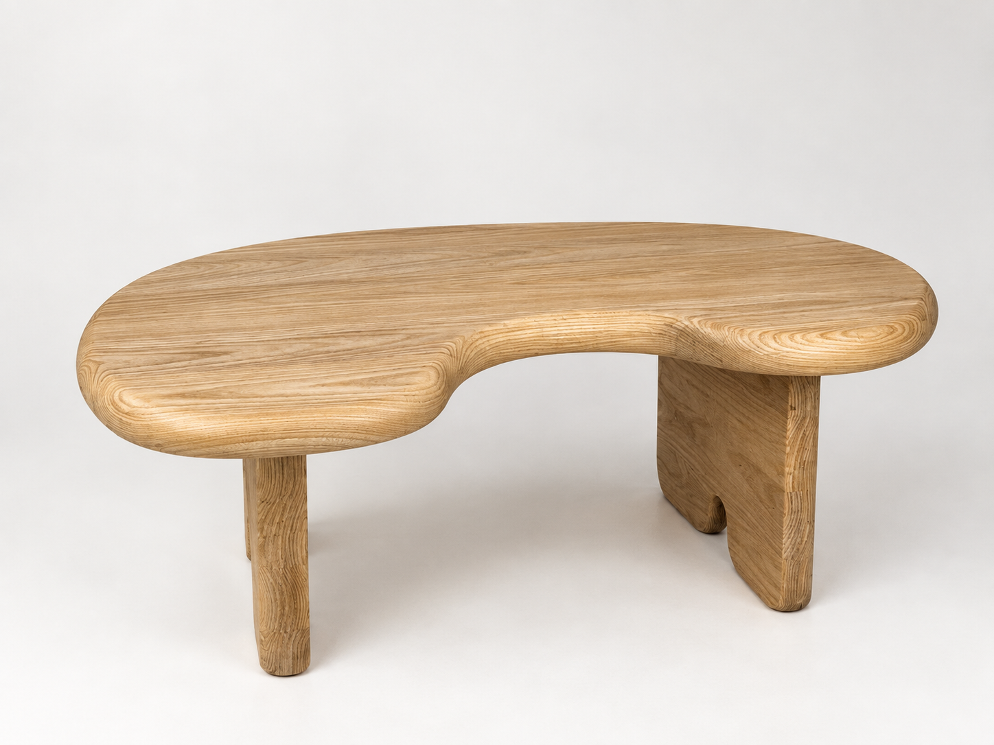 A wooden bench with a curved top and three thick legs, made of light-colored wood, on a plain white background.