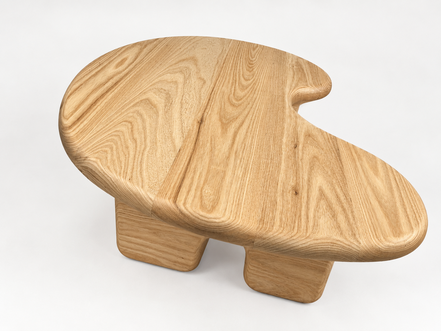 A wooden, abstractly shaped table with smooth curves and a natural wood finish, set against a white background.