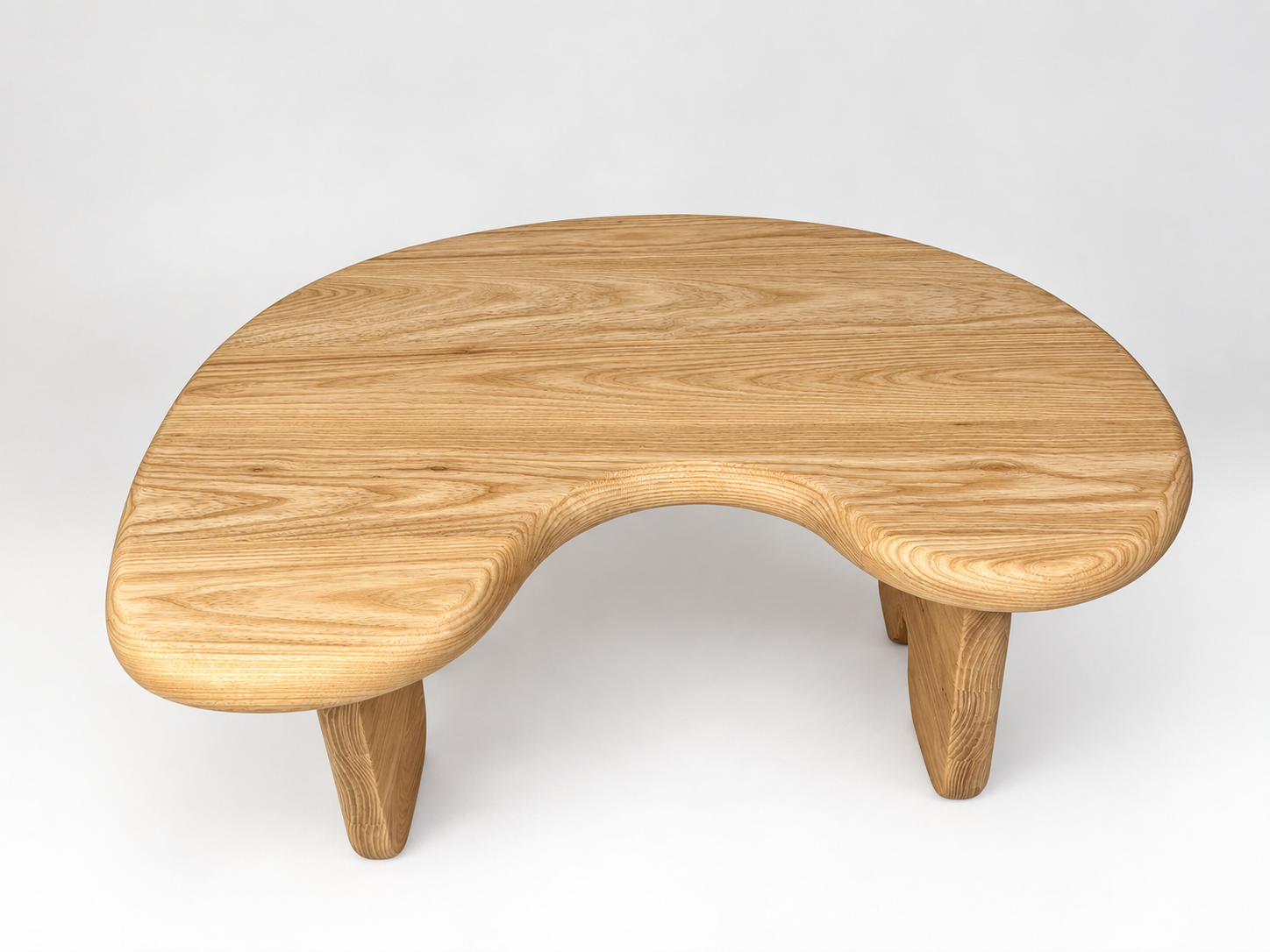 A wooden kidney-shaped coffee table with three rounded legs on a white background.