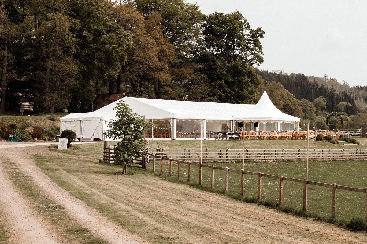 framed marquee with festoon lights and wooden outdoor furniture located in the Scottish Borders